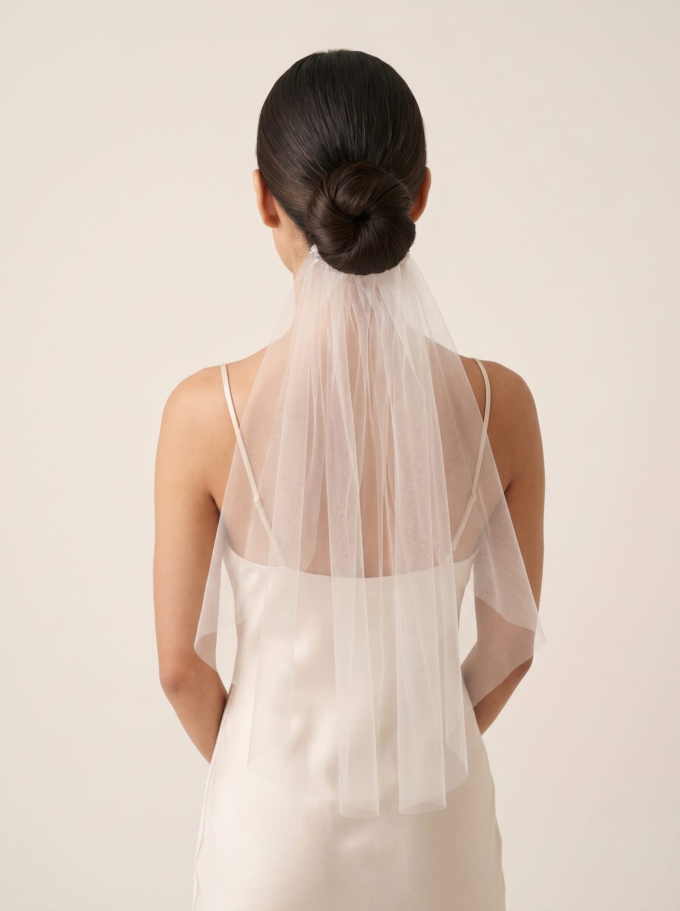 An elegant low bridal updo with a sheer veil
