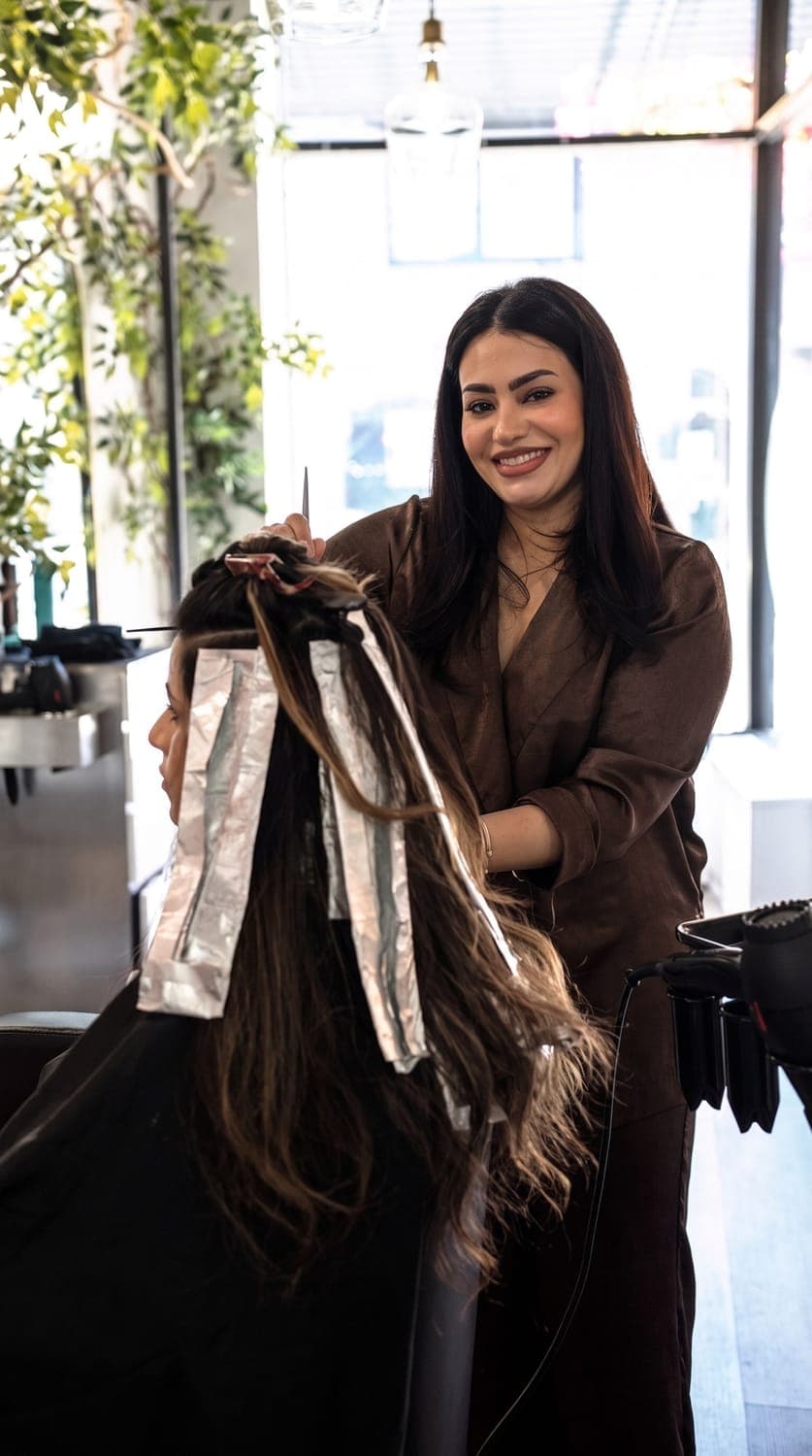 Owner Manijeh hand-painting balayage highlights by the window at House of Excellence 201